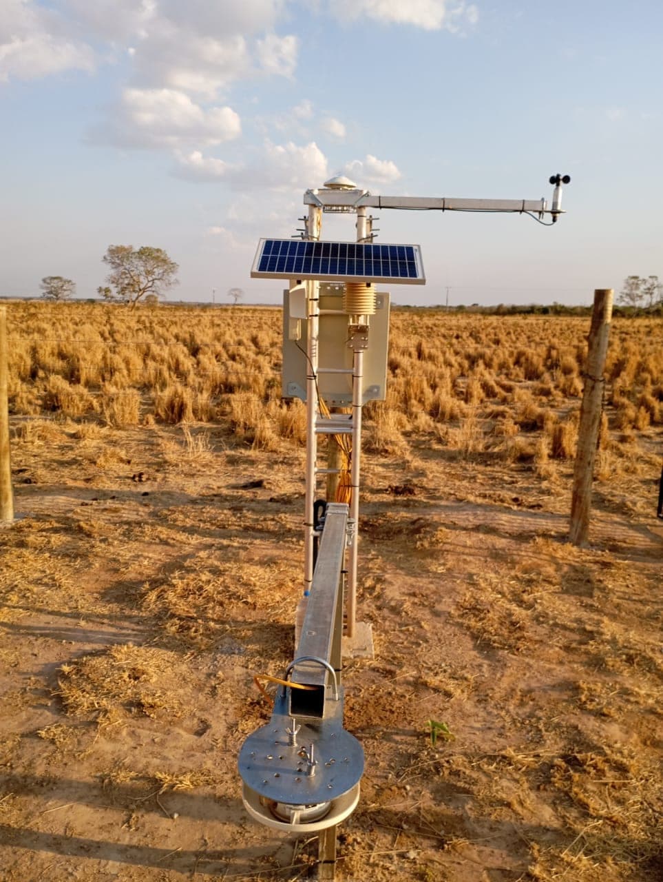 Estação solarimétrica da Brenergy instalada em campo: piranômetro no topo, anemômetro no braço lateral, módulo fotovoltaico e caixa do datalogger
